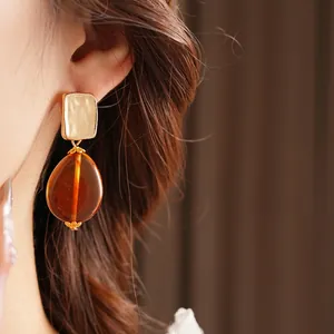 Vintage gold textured square earrings with amber teardrop pendants on model