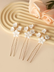 Detailed view of handmade white ceramic flower hair pins with crystals and gold U-shaped pins