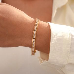 Detail of a minimalist gold tennis bracelet with white crystals on a woman's wrist
