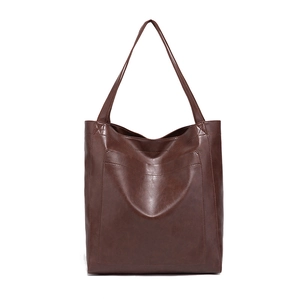 Détail de la texture en cuir ciré marron vintage et poche avant du sac cabas fourre-tout