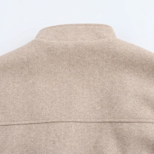 Close-up of beige wool blend fabric texture and stitching detail on the bomber jacket back