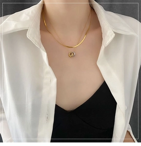 Detail of layered gold snake chain necklace with tricolor interlocking rings on model