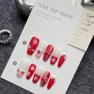 Handmade Christmas press-on nails featuring red bows, snowflakes, and gold glitter accents