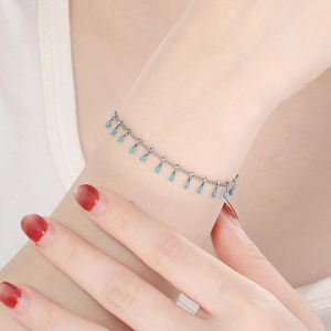Minimalist silver chain bracelet with light blue enamel drop pendants on female wrist