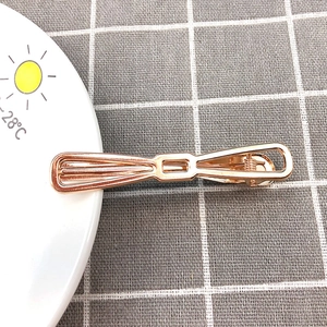 Rose gold metal bow hair clip on a white plate with minimalist aesthetic background