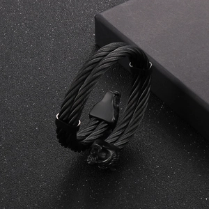 Macro detail of men's black steel wire cable bracelet with wolf head punk style ornaments