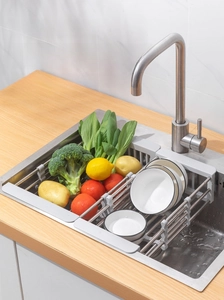 Close-up of expandable stainless steel sink colander basket holding fresh vegetables and a bowl