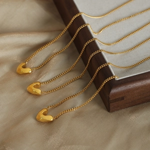 Trois colliers avec pendentifs cœur dorés posés sur de la soie champagne chic