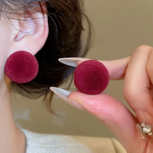 Macro shot of dark burgundy flocked spherical stud earrings with velvet texture