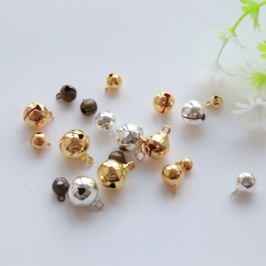 Macro shot of assorted gold, silver and bronze metal DIY craft bells on a white background