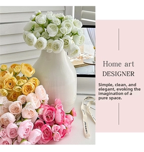 Artificial ranunculus flowers in white ceramic vase near bright window shutter