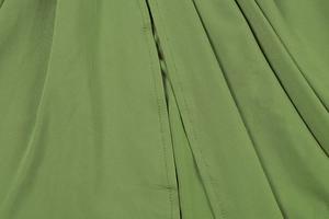Detail of olive green fabric featuring fine stitching and pleated texture on beach dress