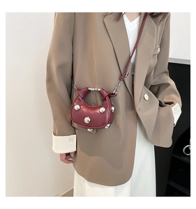 Detail of burgundy crescent mini bag with silver spherical studs on khaki blazer