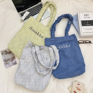 Three plaid canvas tote bags with ruched handles shown in a lifestyle campus setting