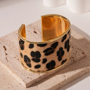Detailed view of leopard print faux fur inlay on a wide gold-plated cuff bracelet