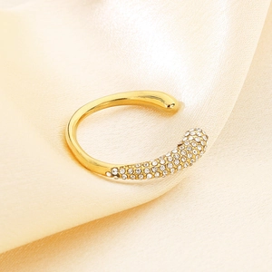 Close-up of golden stainless steel ring with micro-pave crystals on soft textured fabric