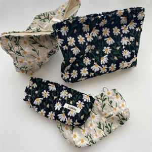 Flat lay view of black and beige daisy embroidered fabric makeup pouches with zippers