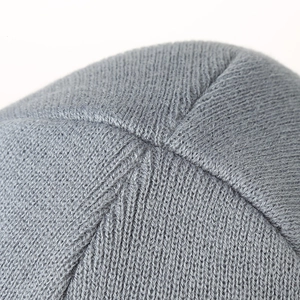 Detailaufnahme der Nähte und der dichten Stricktextur einer grauen Winterstrickmütze