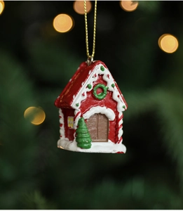 Macro shot of a red gingerbread house ornament with a snow roof on a festive tree
