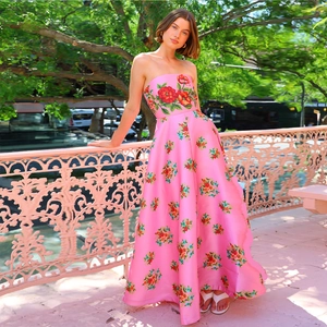 Detail eines rosa Satin-Kleides mit Blumenmuster, trägerlosem Mieder und hoher Taille