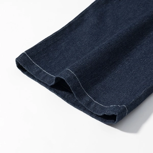 Détail de la double couture blanche sur l'ourlet du pantalon en jean bleu foncé