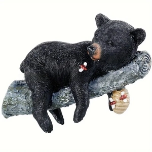Detailed resin black bear sleeping on tree branch with a hanging beehive garden decor