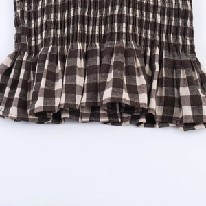 Close-up of black and white honeycomb gingham fabric with elastic smocking and ruffle hem