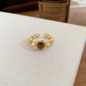 Detail of gold-plated tiger eye ring with hollow link band on white canvas texture