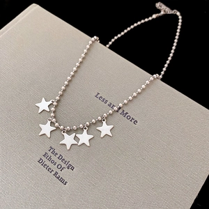 Macro shot of S925 sterling silver ball chain necklace with polished star charms on a book