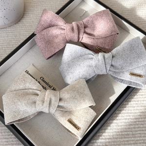 Three elegant bow hair clips in velvet fabric with handmade metal tag on a display tray