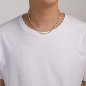 Classic gold tennis chain necklace with zircon stones worn by model on white shirt