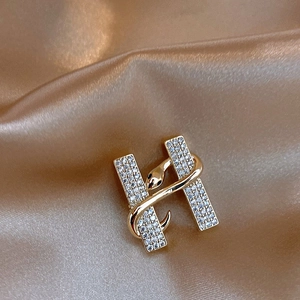 Macro detail of 14k gold plated letter H brooch with pavé stones and snake wrap
