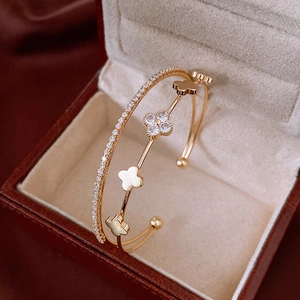 Detail of gold clover bangle featuring zircon pavé layers on a rich red silk background