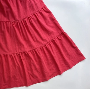 Close-up of red tiered maxi dress showing natural woven fabric and ruffle stitching detail