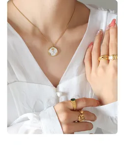 Detail of gold necklace with white enamel rose pendant and matching stacked rings