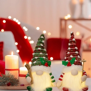 Set of two glowing Christmas gnomes with LED lights and knitted hats on a cozy background