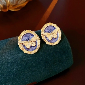 Macro view of vintage gold stud earring with blue enamel and relief butterfly motif