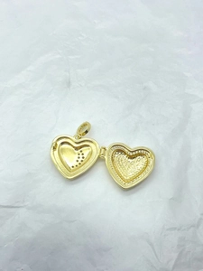 Macro shot of 925 gold plated heart locket pendant with crystal inlay on white paper