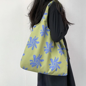 Detail of green floral canvas tote bag showing large capacity and artistic swirl pattern