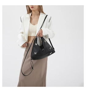 Fashionable black tote bag with silver butterfly ornaments styled on a professional model