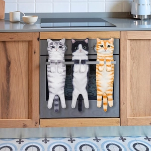 Three cute hanging cat hand towels in grey, orange, and black-white on an oven handle