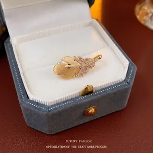 Exquisite golden feather brooch with zircons and matte finish on blue velvet box