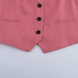 Detail of pink linen blend vest featuring black buttons, side pocket, and fabric texture