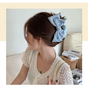 Detailed view of a large light blue satin bow hair claw clip worn by a model