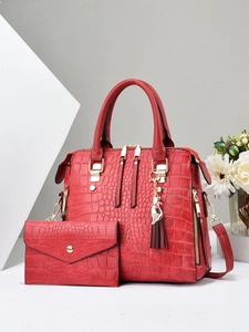 Detail of red embossed crocodile pattern handbag set with golden cat charm tassel