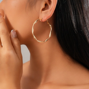 Boucles d'oreilles créoles torsadées dorées au design vintage sur un modèle