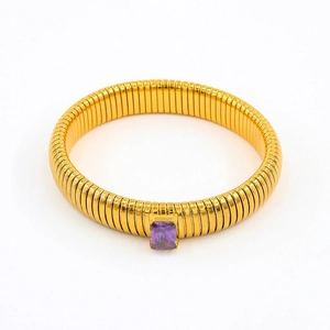 Macro detail of golden Tubogas snake bracelet featuring a faceted purple zircon stone