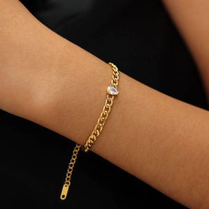 Gros plan d'un bracelet gourmette doré avec zircons en goutte au poignet