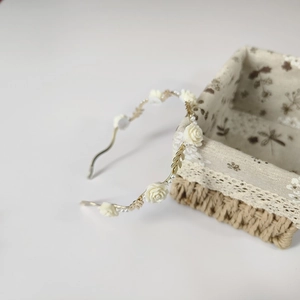 Detailed view of the gold headband with elegant faux pearls and white resin flowers