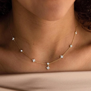 Nahaufnahme der goldenen Kleeblatt-Halskette mit Diamanten auf der Haut eines Modells
